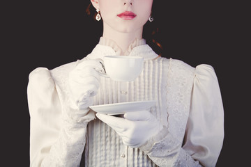 woman in white victorian era clothes with cup of tea