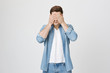© Cookie Studio - Portrait of serious handsome boy, covering eyes with hands and standing over gray background. Freelancer rubbing eyes because of tiredness. Man escapes from reality and duties.