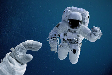 Astronaut reaching out for colleague during space walk 