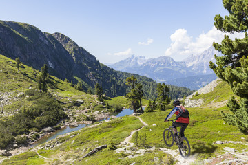 Mountainbiker downhill on Reiteralm with mountain Dachstein in Styria Austria