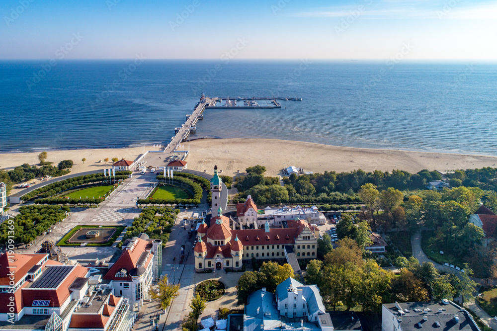 Sopot resort in Poland. SPA, old lighthouse, wooden pier (molo) with marina, yachts,  beach,  vacation infrastructure, park, promenade and walking people. Aerial view. - obrazy, fototapety, plakaty 