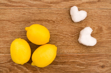 Three lemons and two hearts from snow on a wooden table