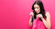 © Tierney - Young woman holding a tiny shopping bag on a pink background