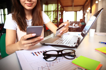 Young woman holding credit card and using laptop computer. Online shopping concept.