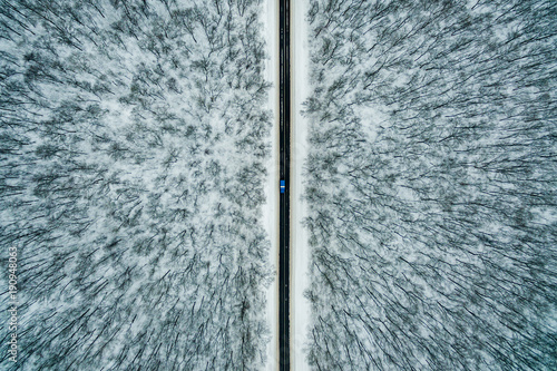 niebieski-samochod-jedzie-wzdluz-drogi-przez-zimowy-las-droga-widziana-z-powietrza-krajobraz-z-lotu-ptaka-fotografia-dronowa