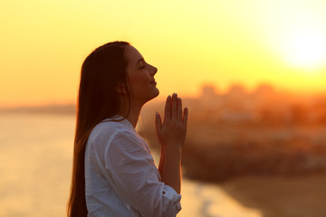 profile of a woman praying at sunset