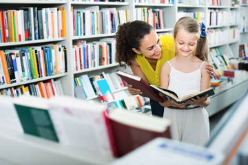 Poster - Cheerful woman with child reading open book