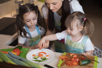 happy family mother and kids are preparing healthy food, they improvise together in the kitchen