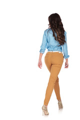 Wall Mural - back view of a young casual woman walking