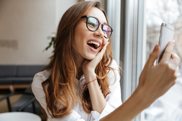 Poster - Happy business woman sitting indoors talking by phone