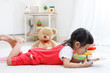 © DN6 - Preschooler girl plaing tablet. Cute child reading with teddy bear. Little girl having fun indoors at home, kindergarten or