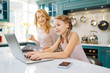 © zinkevych - Nice day. Pretty inspired blond girl smiling and working on the laptop while her mother drinking coffee