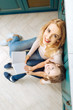 © zinkevych - Reading a book. Good-looking joyful fair-haired mother and daughter smiling and sitting on the floor in the kitchen and reading a book