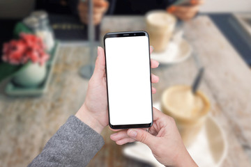 Poster - Smart phone mockup in woman hands. Coffee shop in background, table and plant. Big screen with round edges.