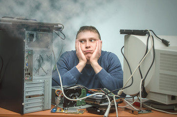 Wall Mural - Tired and bored computer repairman is sitting on his workplace in smoke of burning hardware. Computer technician tired from his work and users. PC repair service center.