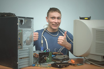 Happy smiling repairman is repairing the computer and is showing a thumbs up. Computer technician. PC repair service center.