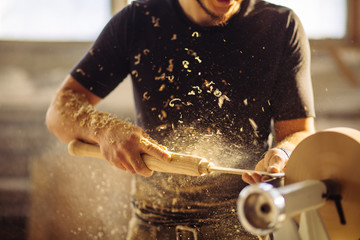 Turner working on a lathe in the workshop. Male hand carved wooden blank