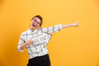 Portrait of funny woman in plaid shirt holding speech arrow pointer with word vacancy isolated over yellow background