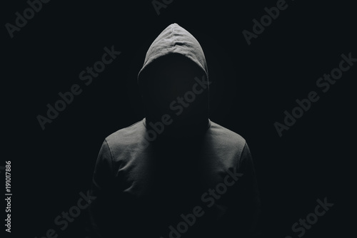 Fotomural faceless man in hoodie standing isolated on black