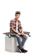 Canvas Print - Teenage hipster with a longboard sitting on a cube