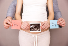 Pregnant Woman With Her Husband Holding Ultrasound Scan And Blue And Red Post Its With Words Boy Or Girl