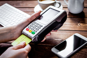 Payment by card in cafe with terminal and keyboard on wooden bac