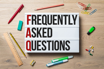 Wall Mural - frequently asked questions written on lightbox lying on desk