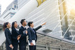 © smilepoker - Group of business peoples standing outdoors with office building in the background, point to target