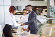 african Customer buying a vehicle at car dealership. woman and man handshaking