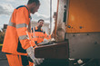 Zwei Müllmänner arbeiten zusammen an der Müllbeseitigung und leeren Mülltonnen 