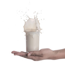 Sticker - Hand holding glass of milk with a splash isolated on a white background