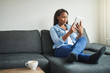 © Flamingo Images - Young African woman relaxing on her sofa with a tablet