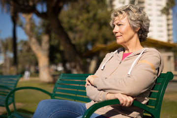 Sticker - Mature caucasian woman sitting on a park bench