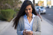 © blvdone - Young Indian woman walking street texting on cell phone