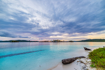 Wall Mural - Tropical beach, caribbean sea, transparent turquoise water, remote Togean Islands (Togian Islands), Sulawesi, Indonesia. Dramatic sky at sunset.