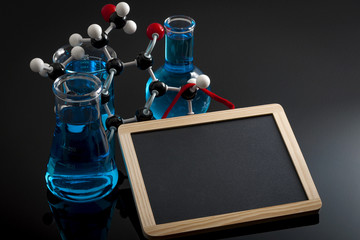 Wall Mural - Chemical reaction, chemistry class and STEM concept with a model of a molecule on chemistry glassware and flasks filled with blue liquid and copy space on a chalkboard