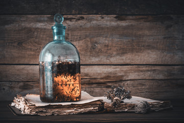 Wall Mural - Tincture or potion bottle, old book and bunch of dry healthy herbs. Herbal medicine. Retro styled.