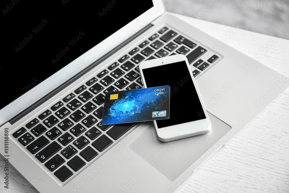 Mobile phone and credit card on laptop keyboard, closeup. Internet shopping concept