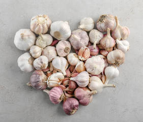 Wall Mural - Heart shape of fresh garlic heads on grey background