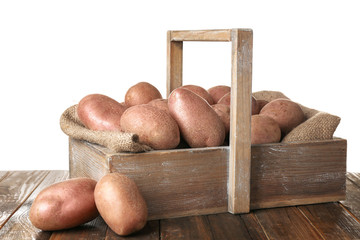 Sticker - Wooden basket with fresh raw potatoes on table against white background