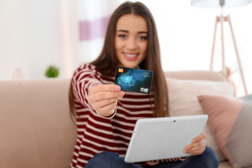 Sticker - Young woman shopping online with credit card and tablet at home