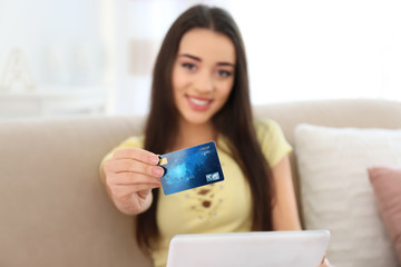 Wall Mural - Young woman shopping online with credit card and tablet at home