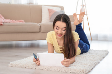 Sticker - Young woman shopping online with credit card and tablet at home