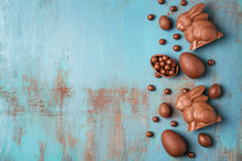 Chocolate Easter Bunnies And Candies On Wooden Background