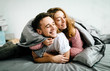 © stakhov - Cheerful couple under the coverlet in their bed. Artwork. Soft focus on the guy