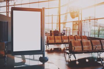 Wall Mural - Close-up blank white advertising banner placeholder template indoors of departure area of modern airport terminal near gate with number 30; empty billboard mock-up near wooden seats in waiting hall