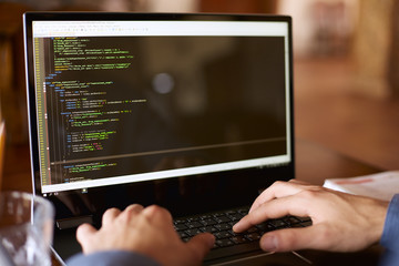 back view over the shoulder shot of developer programmer with laptop. program code and script data o