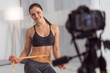 © zinkevych - Being slim. Beautiful vigorous athletic young woman holding a waist tape measure and smiling while making a video for her blog