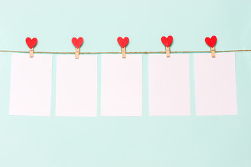 white pieces of paper pinned to rope with clothespins decorated with wooden hearts