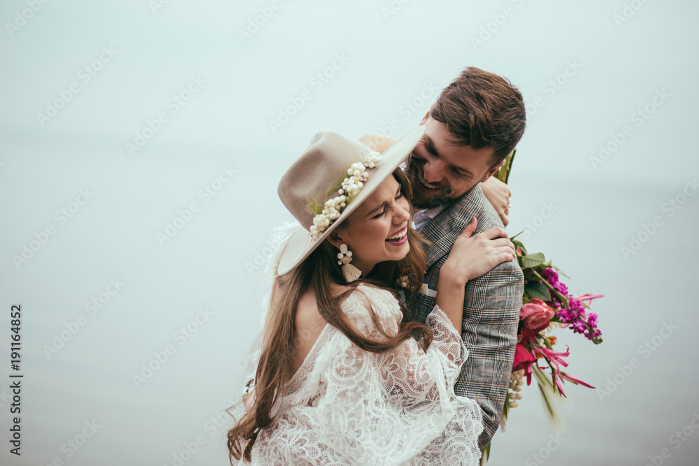 Obraz na płótnie beautiful happy bride and groom in boho style laughing at lake w salonie